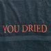 Gros plan sur les lettres "YOU DRIED" brodées en rouge